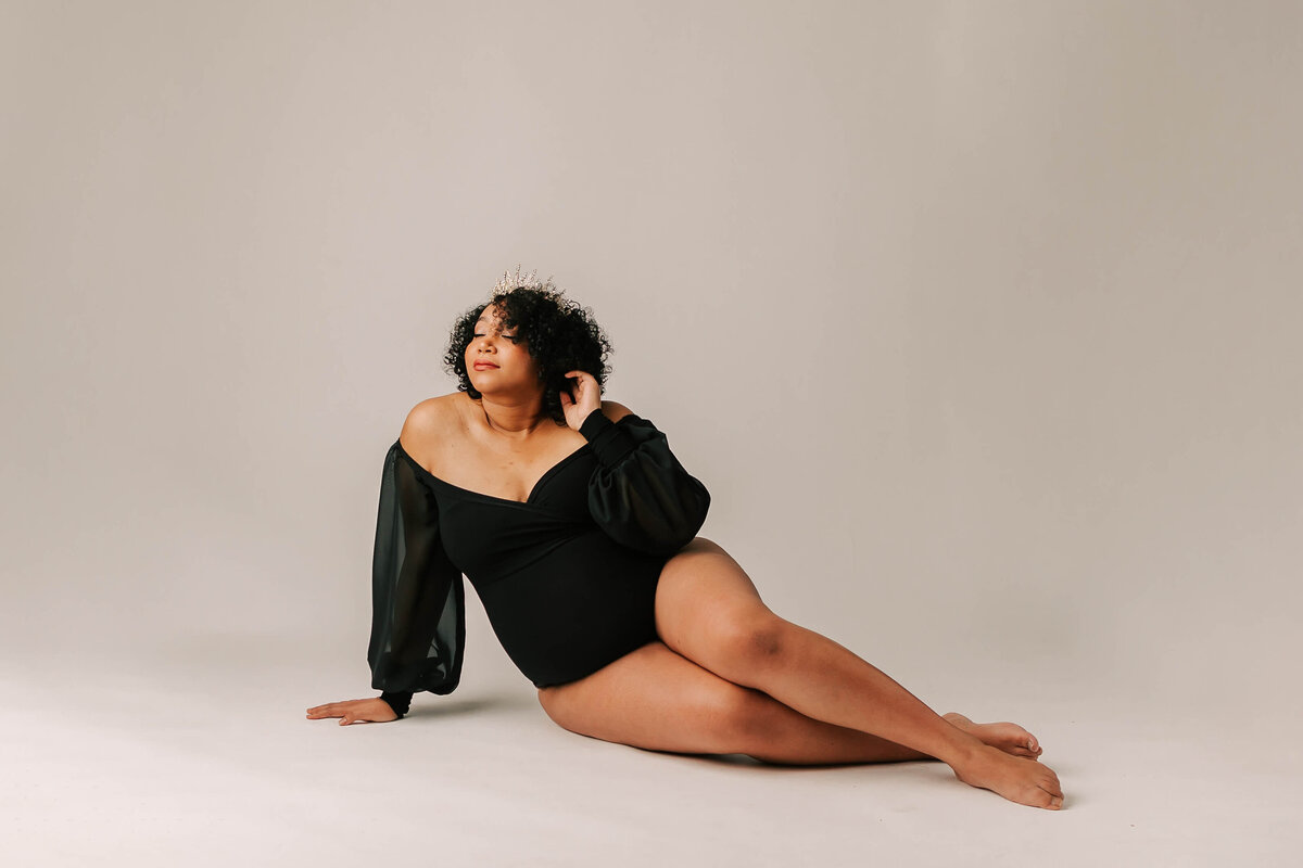 mom wearing black leotard sitting down for maternity portrait