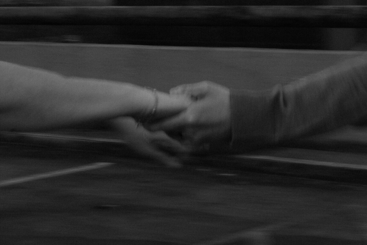 a black and white motion blur photo of two hands holding each other.