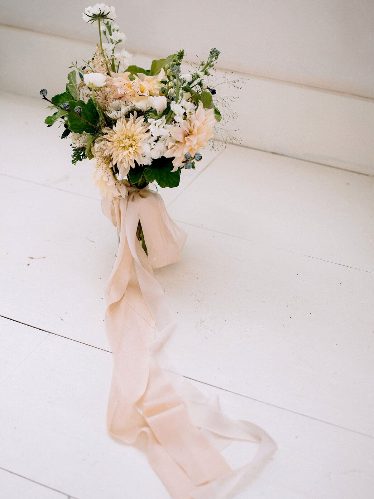 A flower bouquet tied with a cream-colored ribbon in Foxfire Mountain House, New York. Wedding Image by Jenny Fu Studio