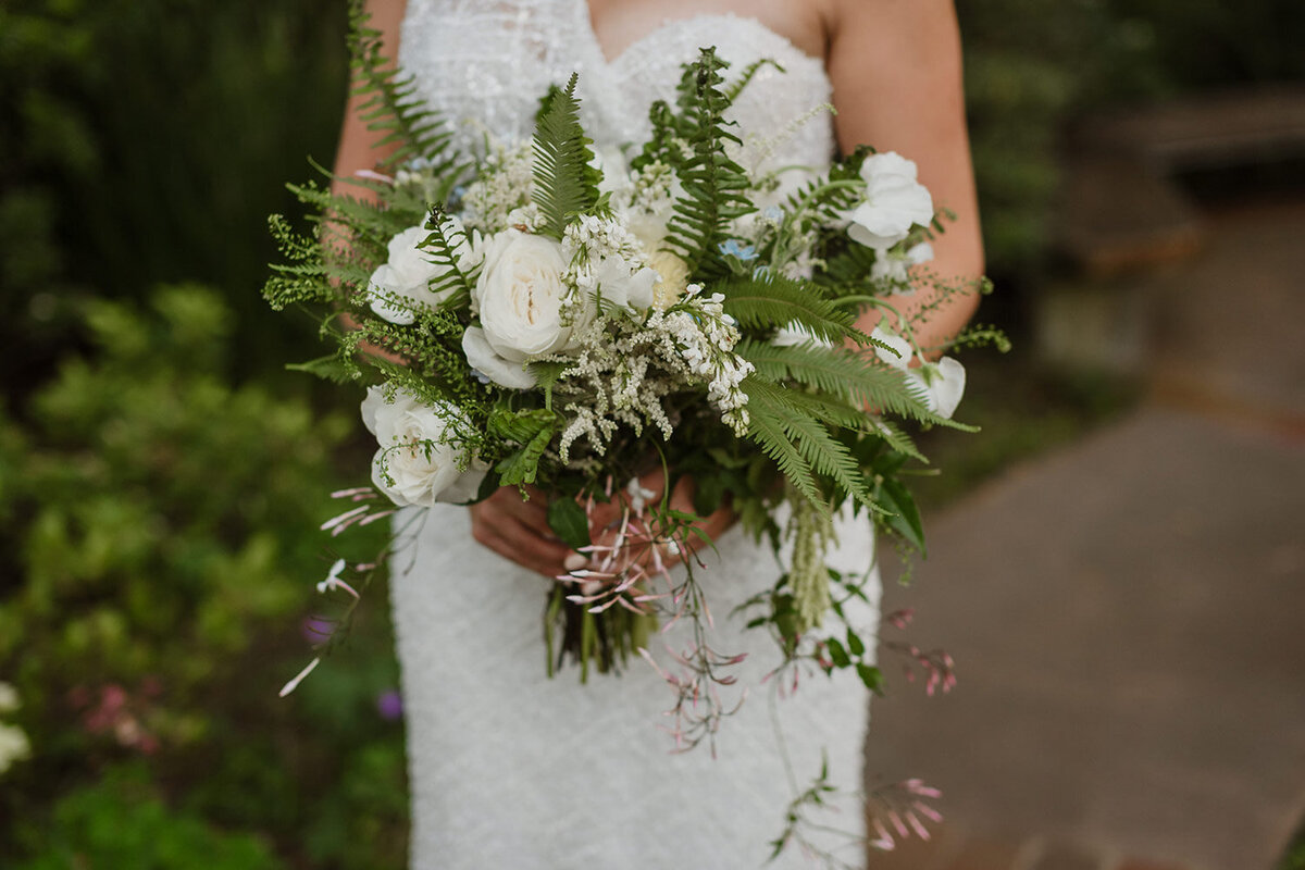 Bride in outdoor venue holding her wedding bouquet