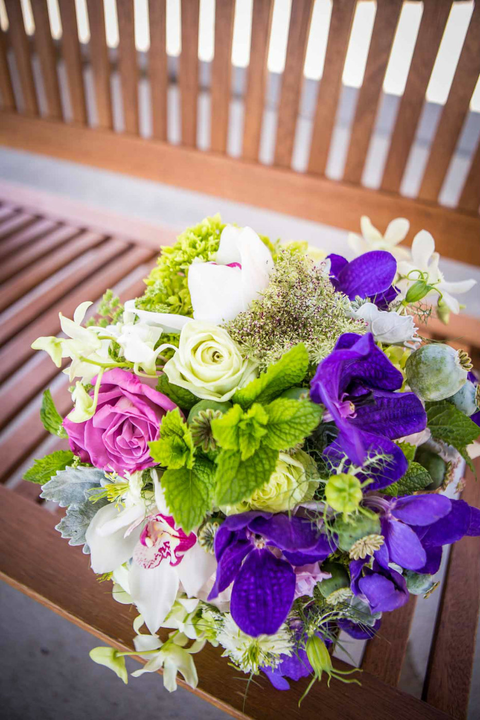 Bridal bouquet of purple roses, purple orchids. white roses, and herbs