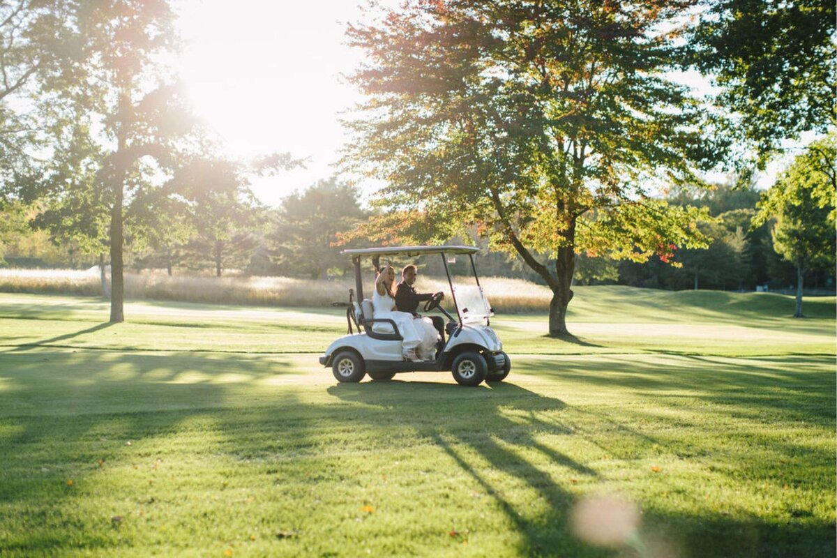 Bride and Groom Arrive to their Reception Via Golfcart for a Luxury Michigan Lakefront Golf Club Wedding.