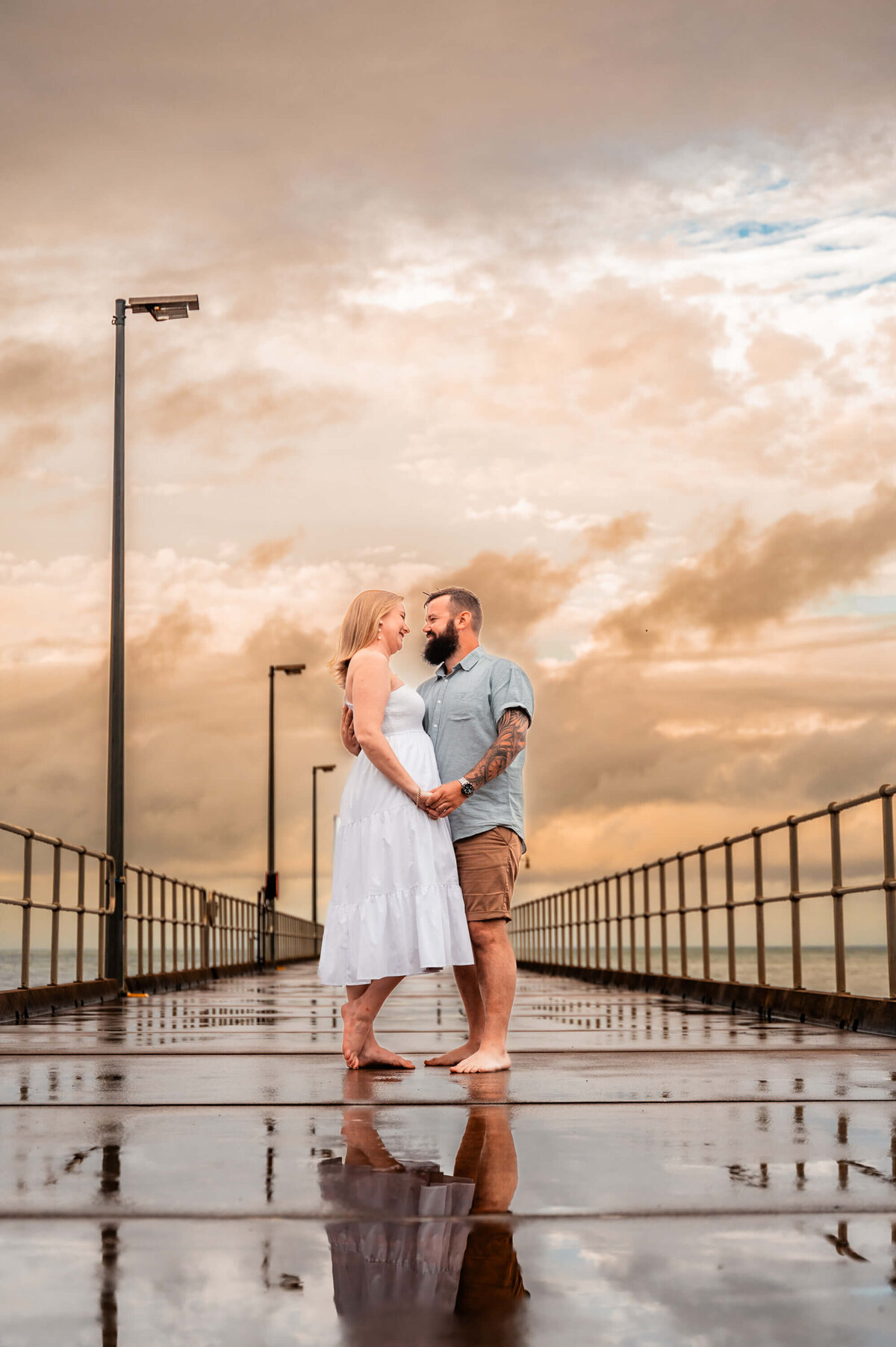 A engaged couple embraces on a pier, silhouetted against a vibrant sunset, capturing a moment of love and anticipation. - photo by Jamie Simmons