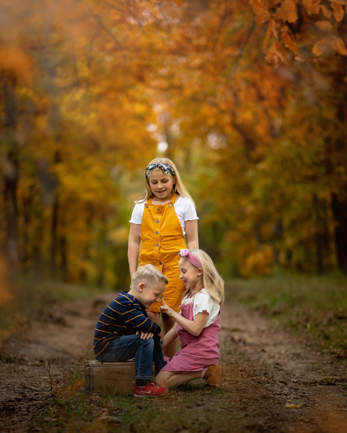 Kids take a seat on a path surrounded by fall colors