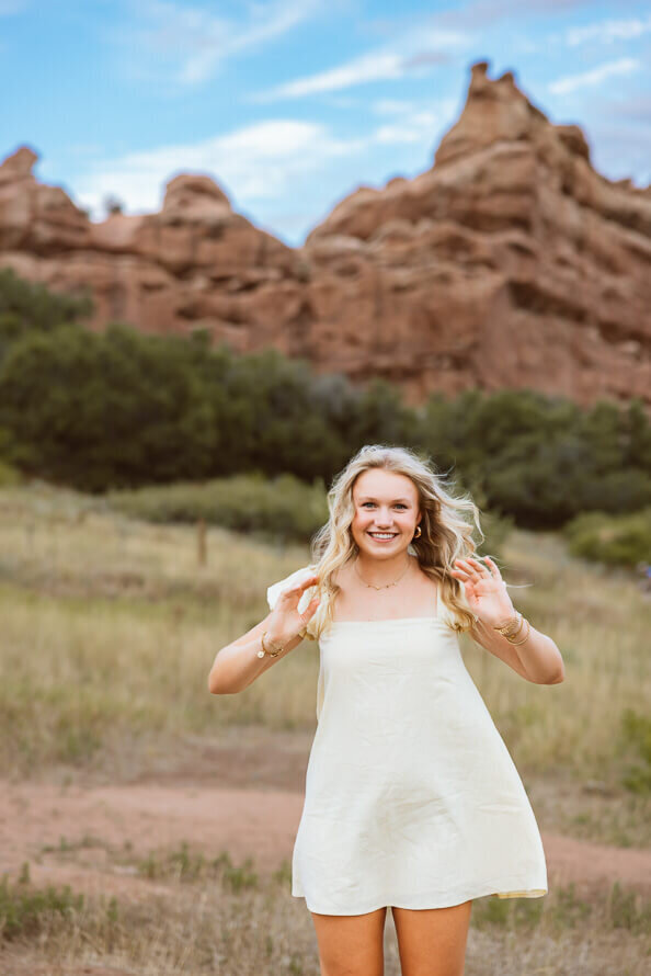 Girl pulls hair forward with red rock formations behind her.