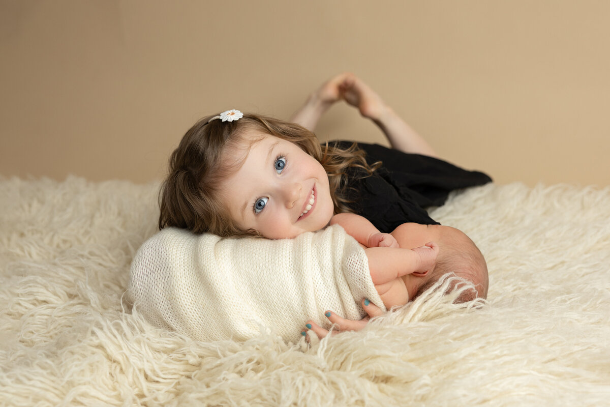 newborn and sister studio flokati pose with savage seamless pecan backdrop