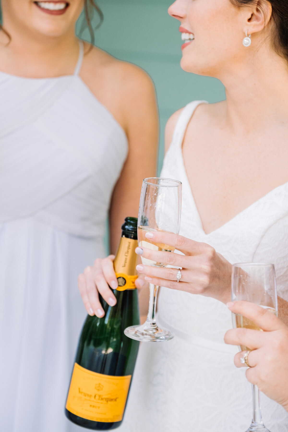 Bride and bridesmaid drink champagne on wedding day