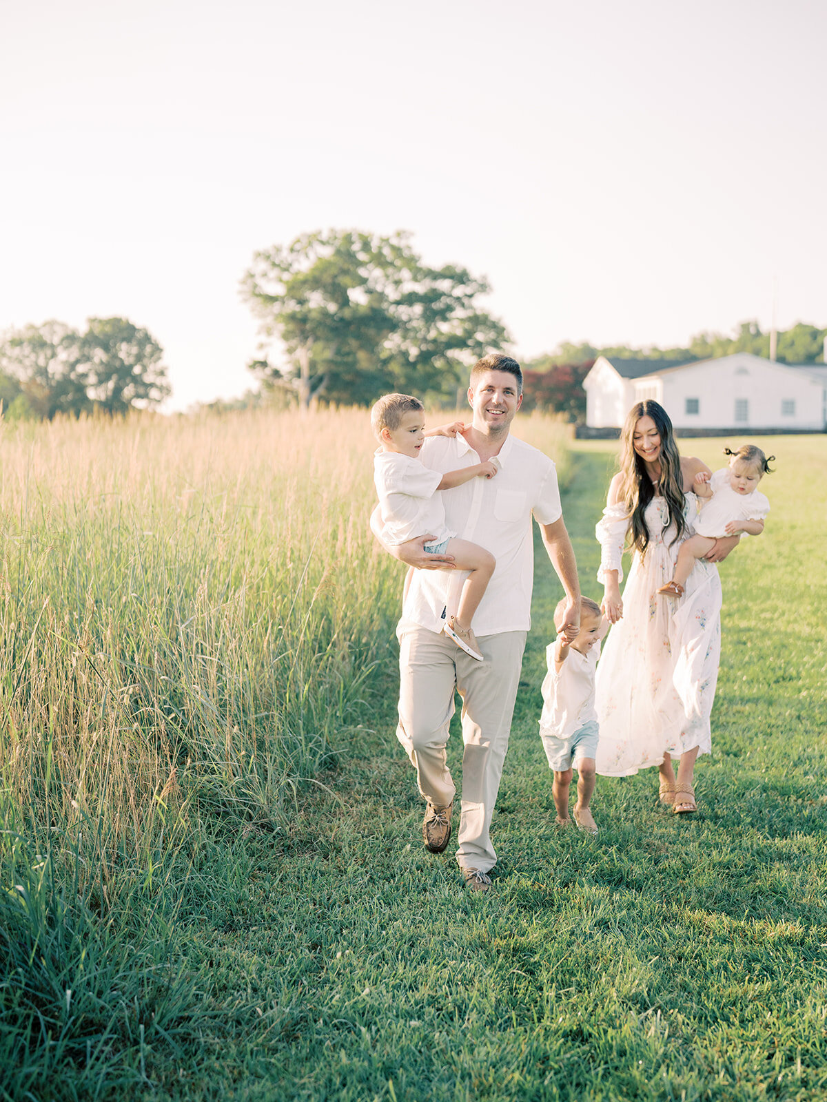 Father leads his family of five along the edge of a field during their family photo session in Northern Virginia.
