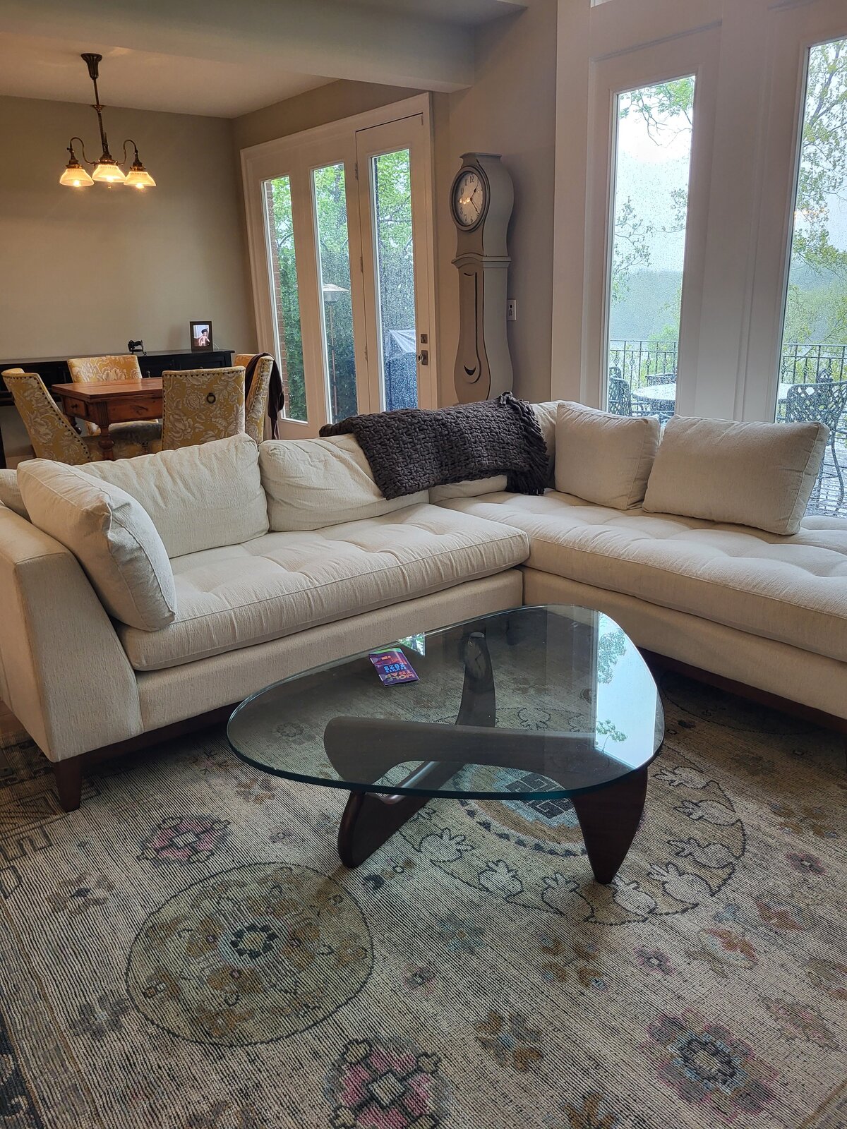 Living room with woven antique rug and Noguchi replication coffee table with cream Arhaus sofa and Moira clock with antique patterened chair