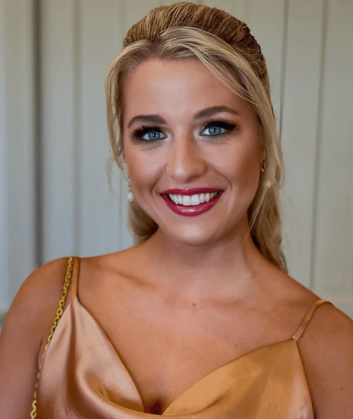 Woman in satin dress with classic updo and bold red lipstick, styled for a special event by Mistique Makeup in San Antonio