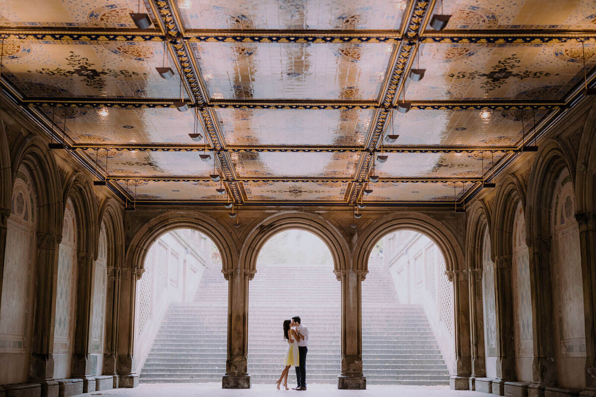 The engaged couple is kissing in the middle of Bethesda Terrace in Central Park. Image by Jenny Fu Studio.