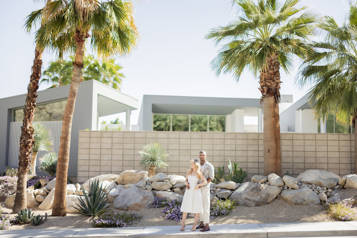Couple walking through a desert garden path in Palm Springs, framed by soft sunlight and lush greenery.