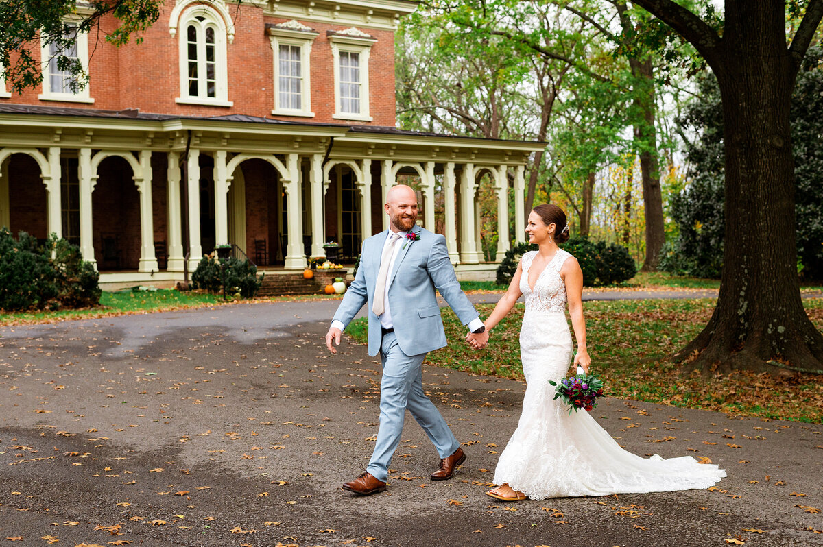 Bride and groom holding hands walking outside of Oaklands Mansion in Murfreesboro