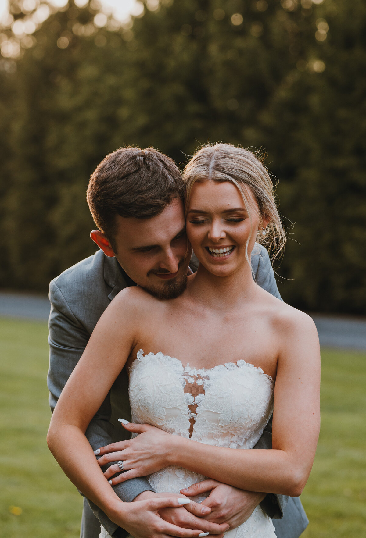 Groom holding bride from behind smiling
