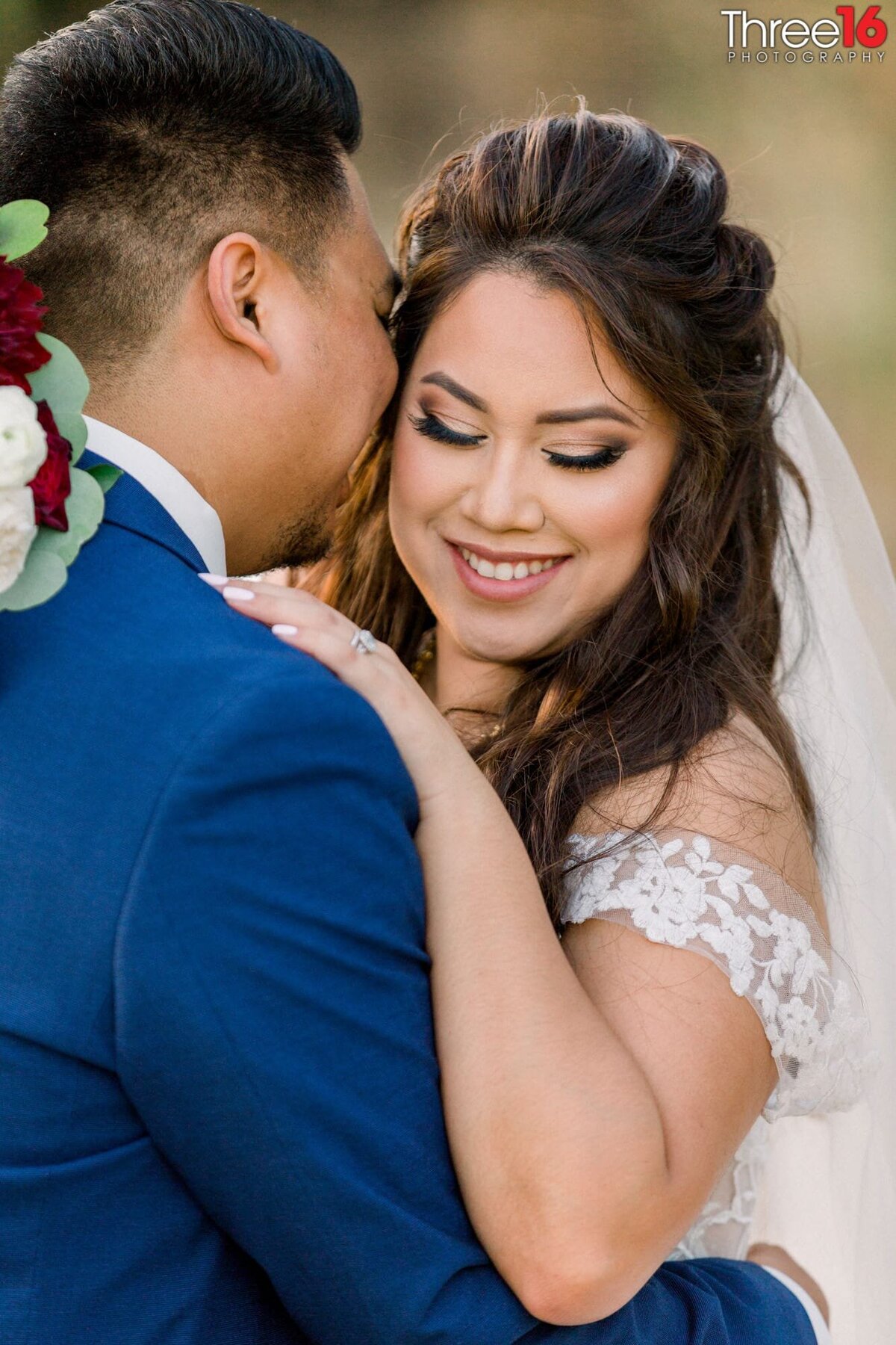 Bride and Groom embrace each other as the Groom whispers into her ear
