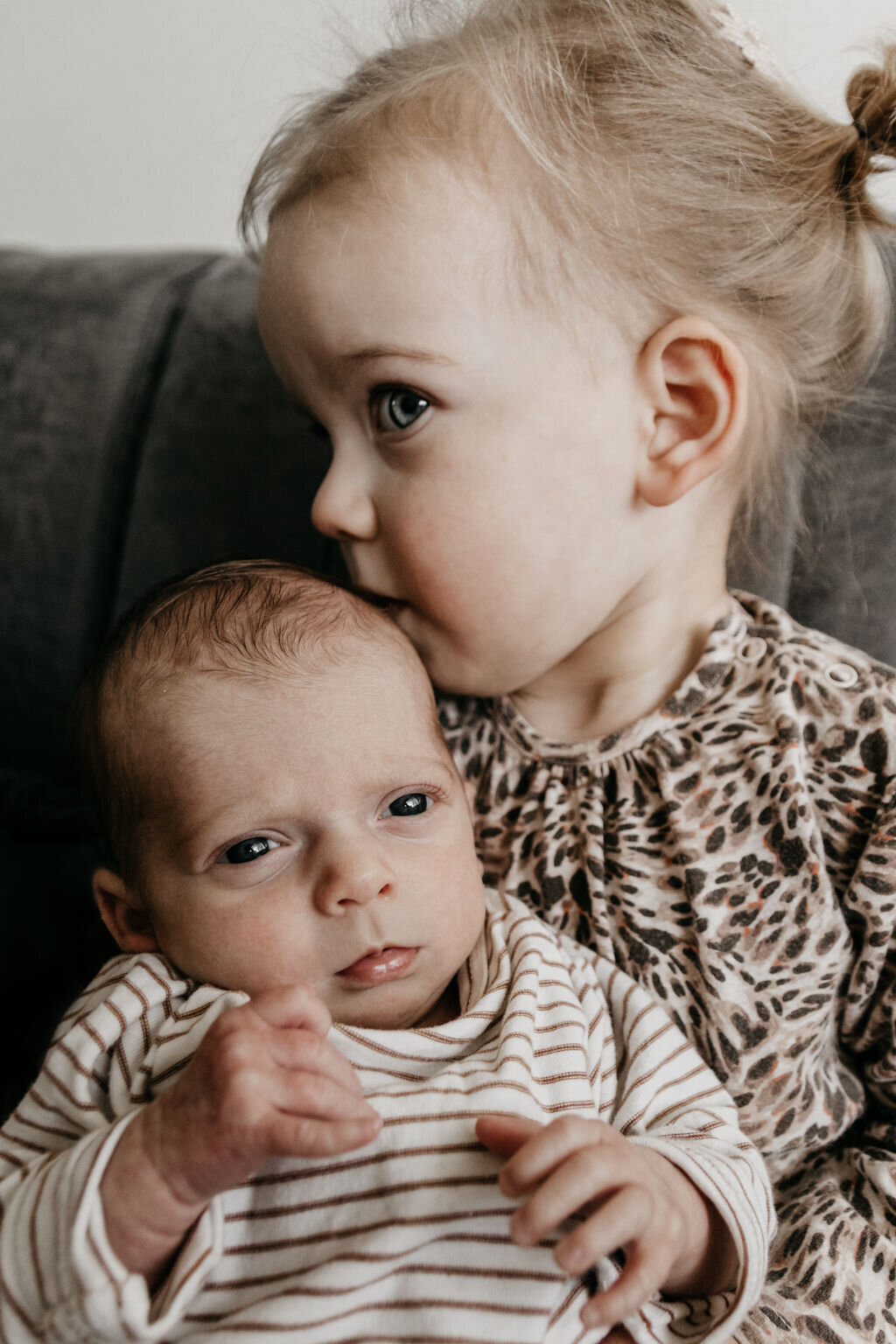 Zusje geeft een kusje aan haar newborn baby broertje tijdens de newbornshoot