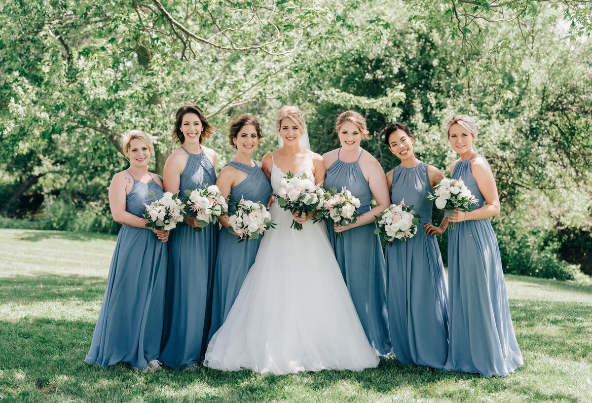 Elegant bride and bridesmaids in light blue dresses during outdoor wedding portraits at Willow Creek Barn photographed by Nova Markina