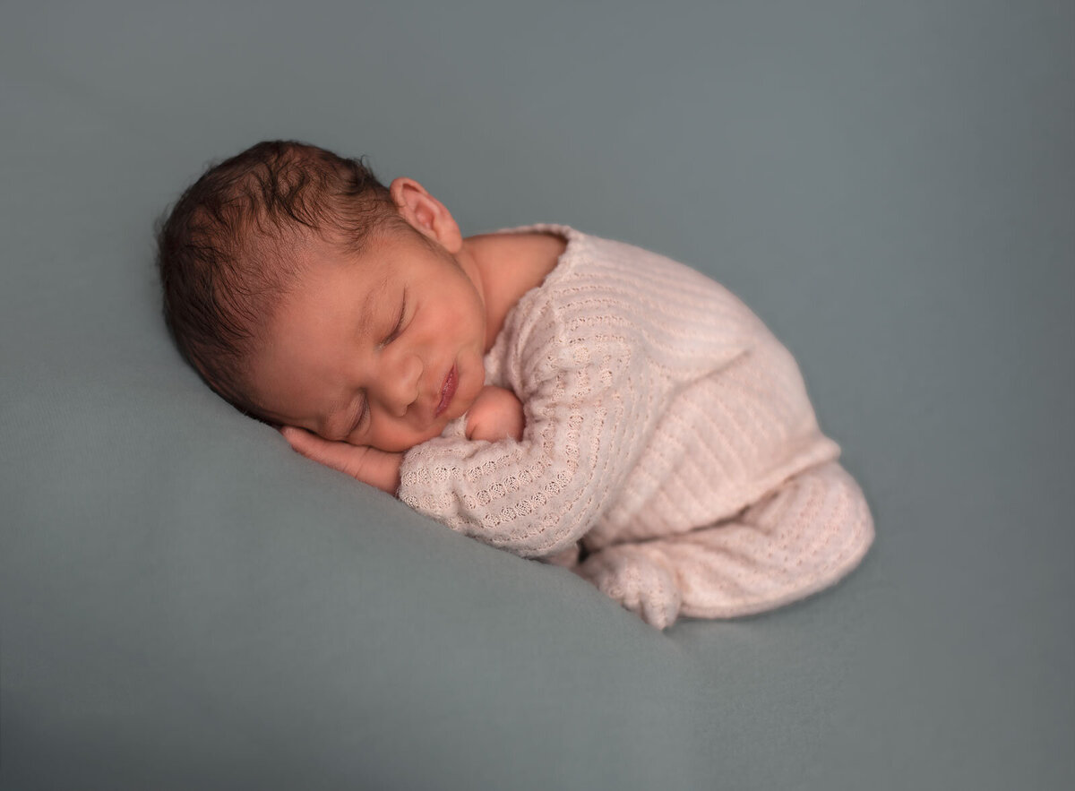 baby sleeping on seafoam blanket in a sleeper at st. louis newborn photo session