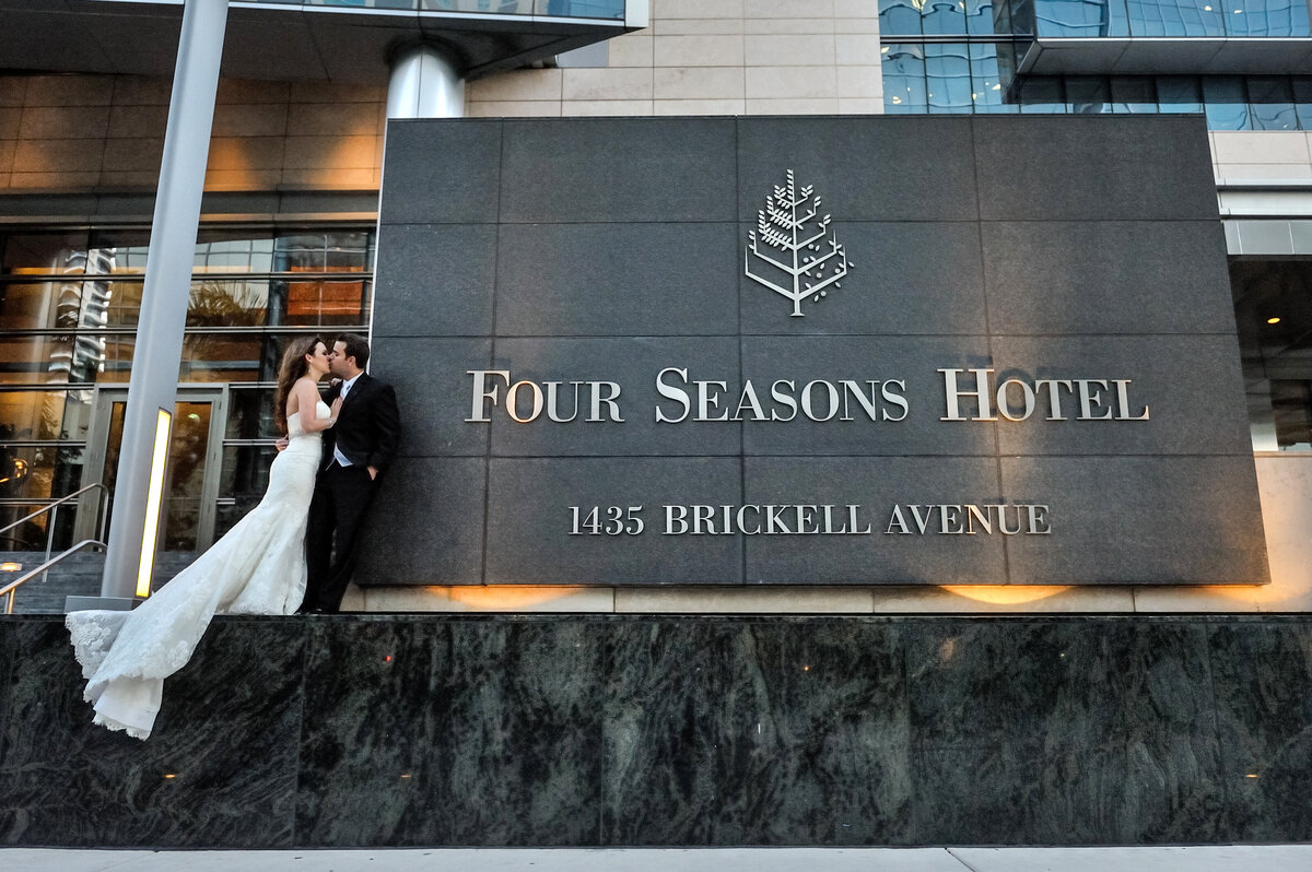 Bride and groom pose against the Four Seasons Hotel signage on Brickell Avenue, Miami.
