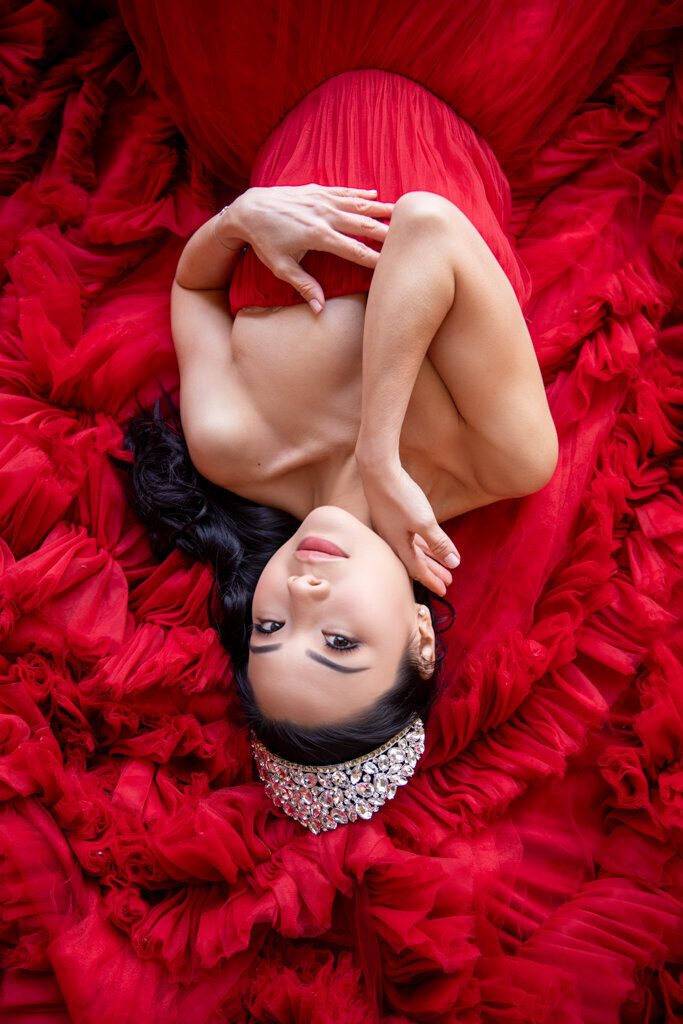 Intimate portrait photography of Asian woman laying on red fluffy dress wearing silver crown