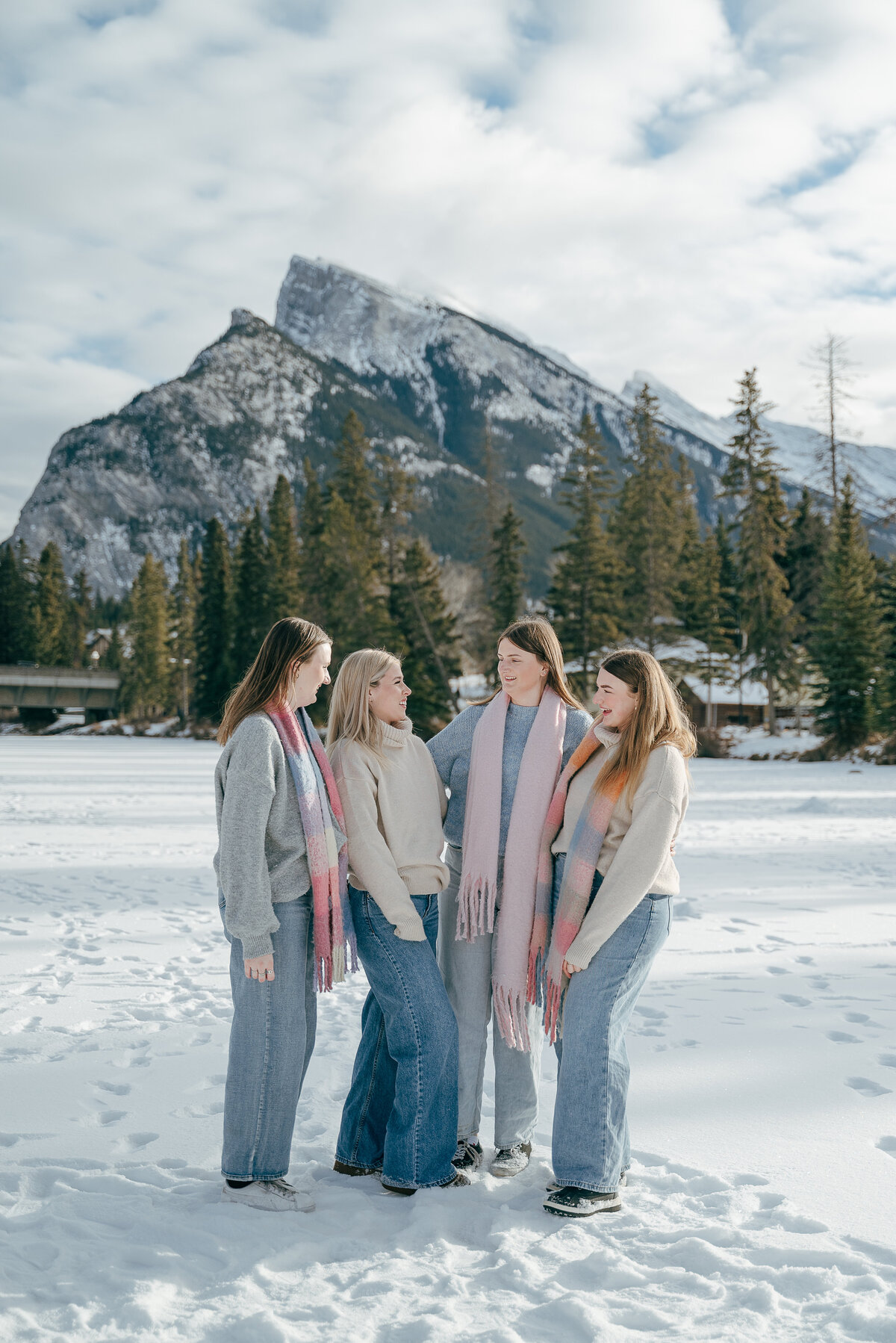 Family smiles in front of snow-covered mountain during winter session in Banff.