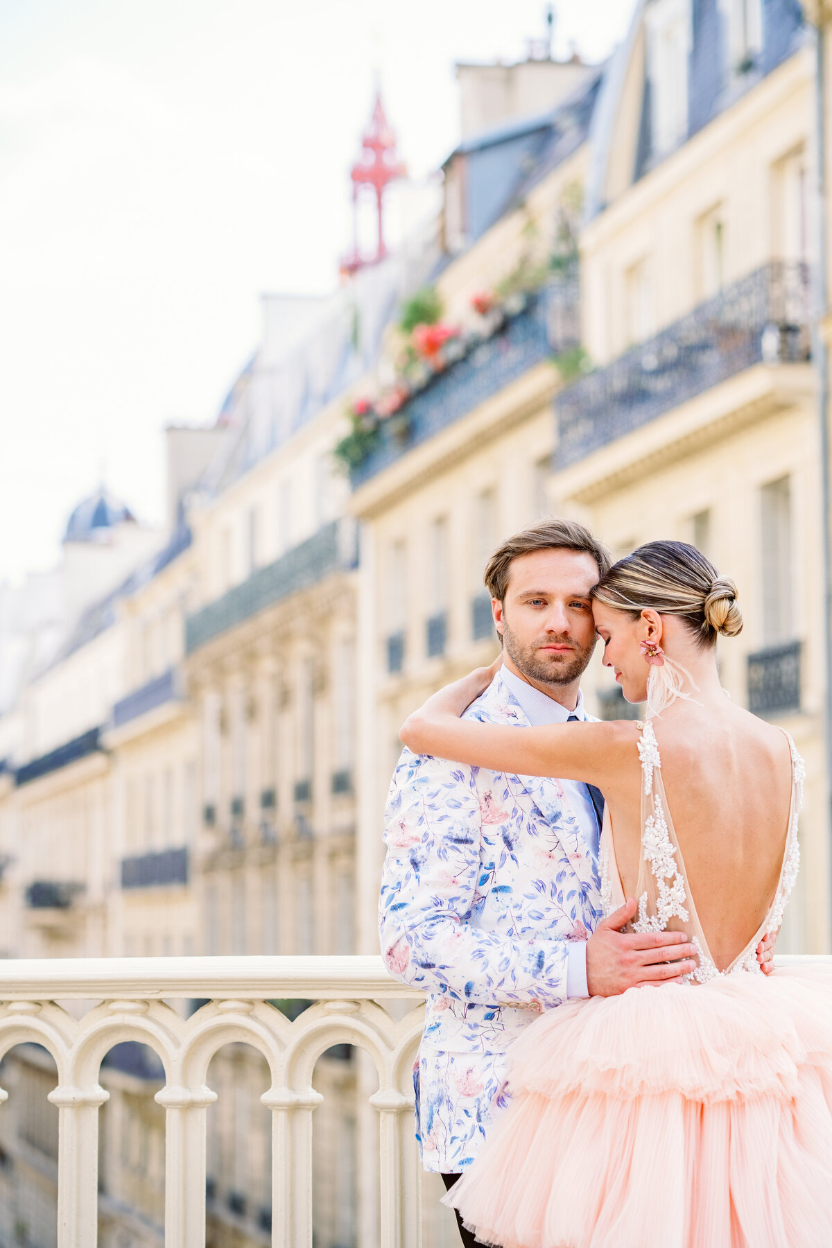 Couple on bridge overlooking a long line of Parisian homes during their Paris engagement session, photographed by Italy wedding photographer.