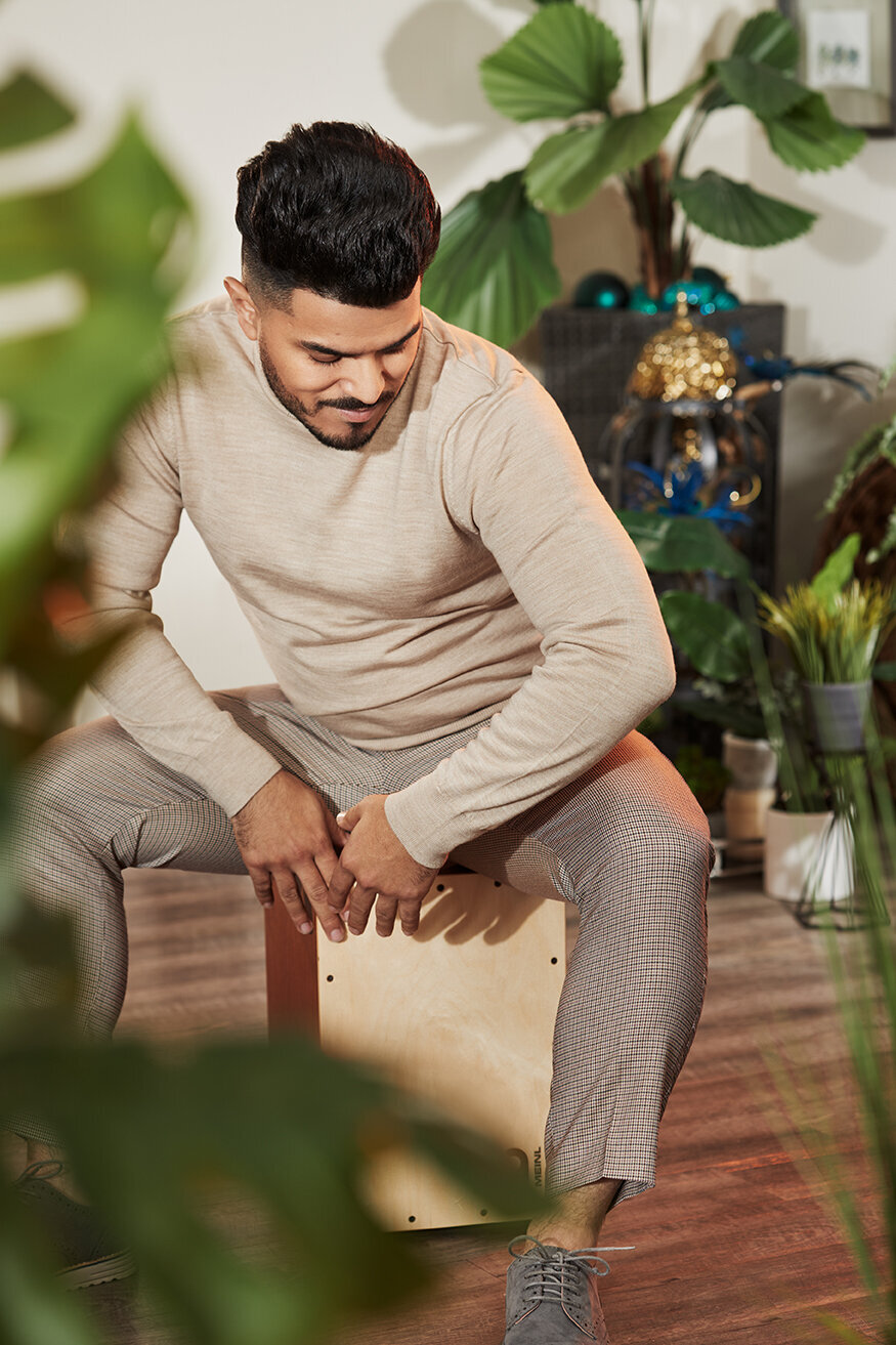 Fashion-forward portrait of Mr. B Styles in a white outfit, seated in a casual outdoor setting, photographed by Ylva Erevall.