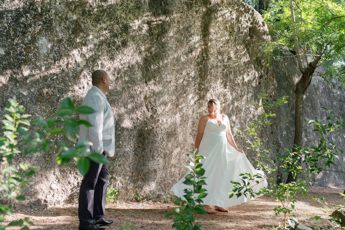 Bride twirling in her dress at elopement in front of stone wall in Austin