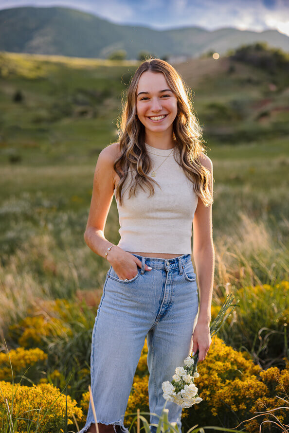 Girl hold flowers and smiles for her senior photos.