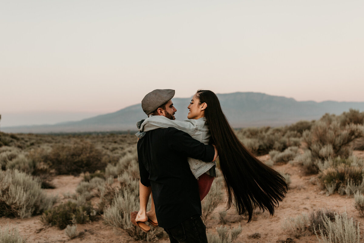 man holding long haired woman in desert