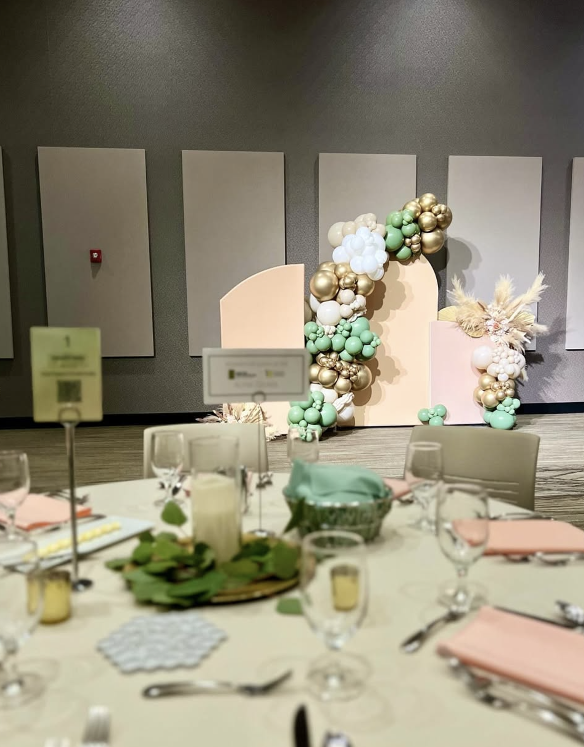 Soft pastel pink and gold balloon backdrop with wicker chairs, ideal for baby showers or bridal events.