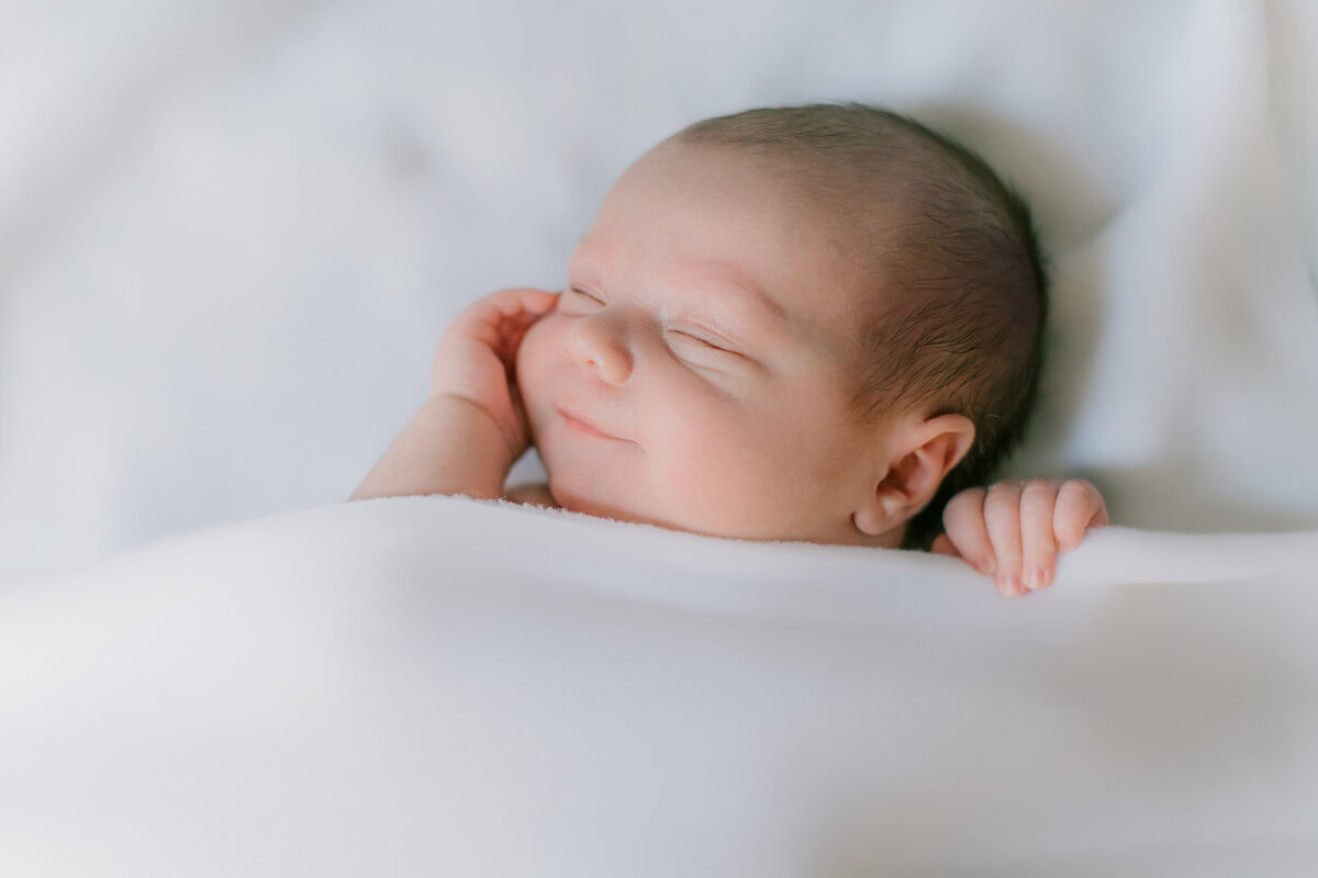 Newborn baby photo session while baby smiles in his sleep
