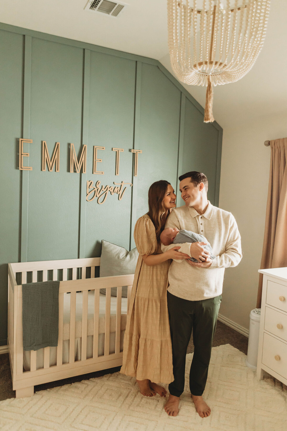 Proud parents holding their newborn baby in his cute nursery.