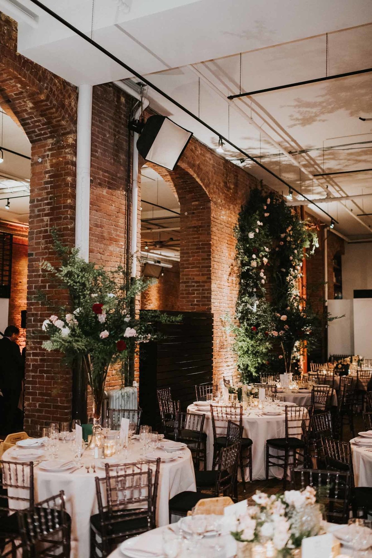 winter wedding reception at Axis Pioneer square with tall greenery centerpieces and a large greenery arch