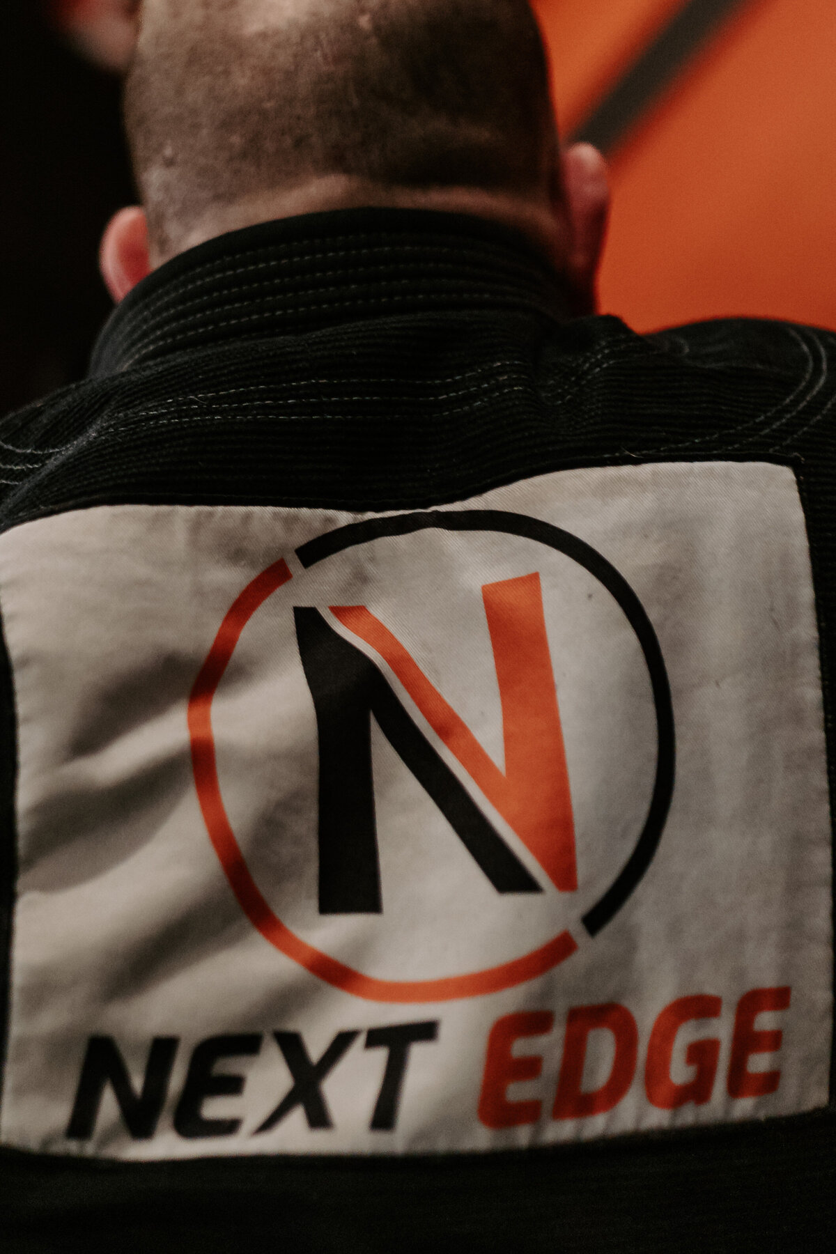A close up view of a logo on the back of a shirt that reads Next Edge