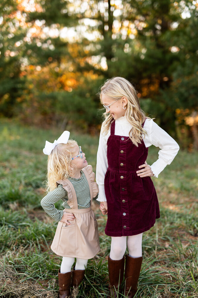Sisters holding hands outdoors during a family session