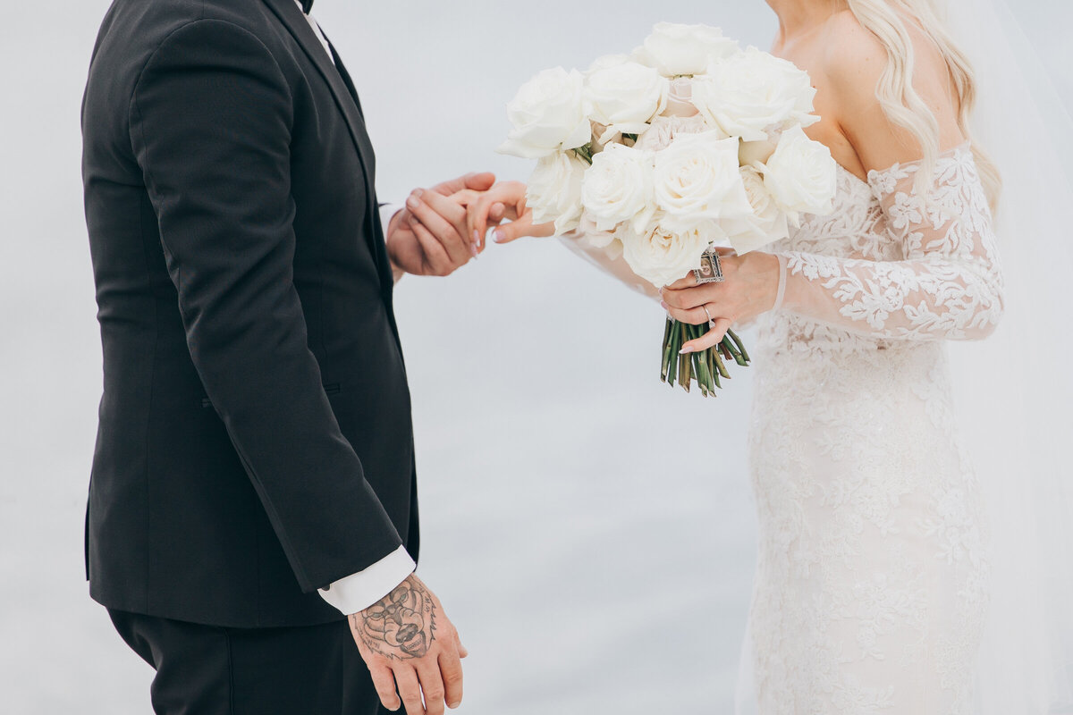 Bride and groom holding luxurious bouquet of magnificent white and pink roses