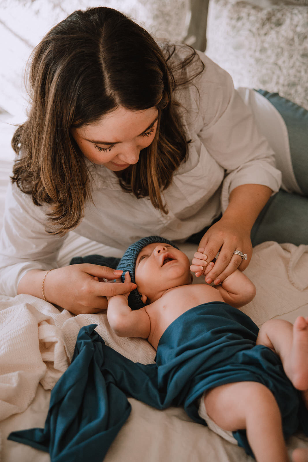 A parent laying down holding their newborns hands 