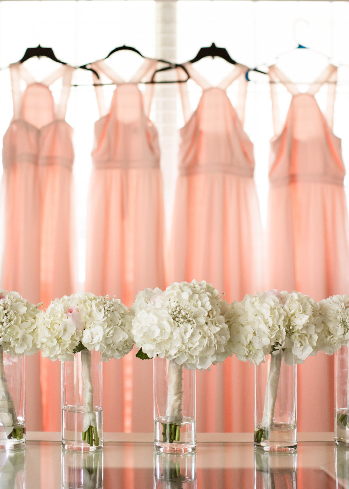 The bridesmaids dresses and flowers hang for a detail photo.