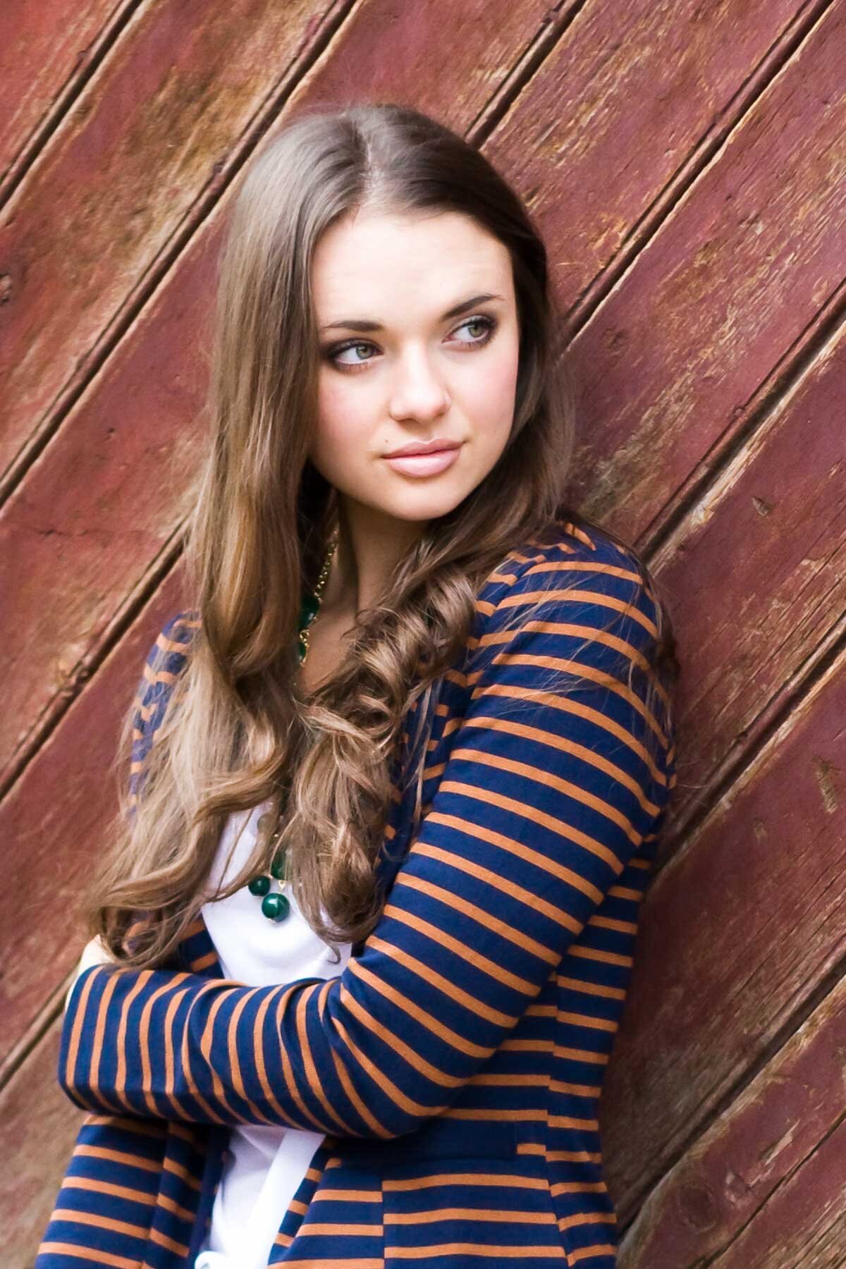 Senior portrait of girl leaning against a wooden plank wall in Lehi, Utah.