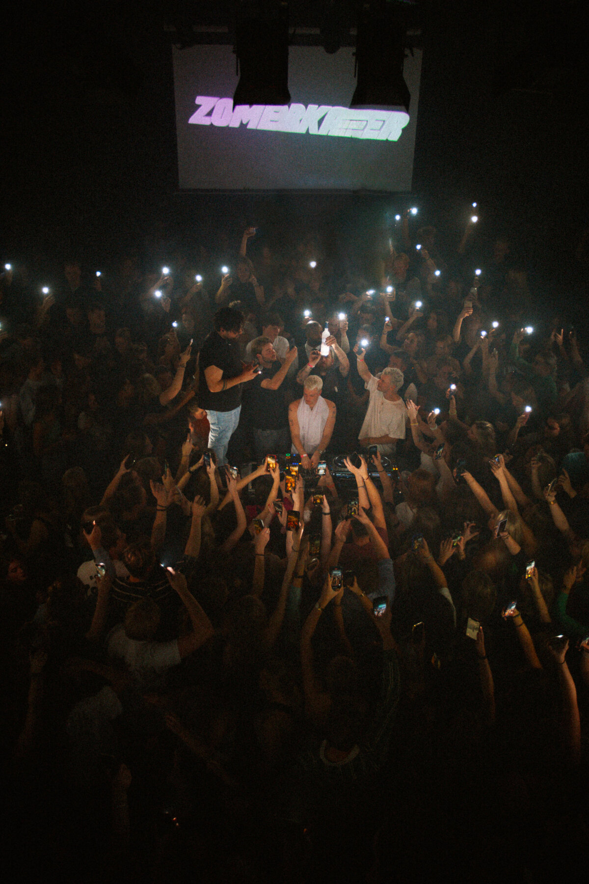 Bo Eppink photographs Sam Hofman from the DJ booth, surrounded by a sea of fans with lights illuminating the night.