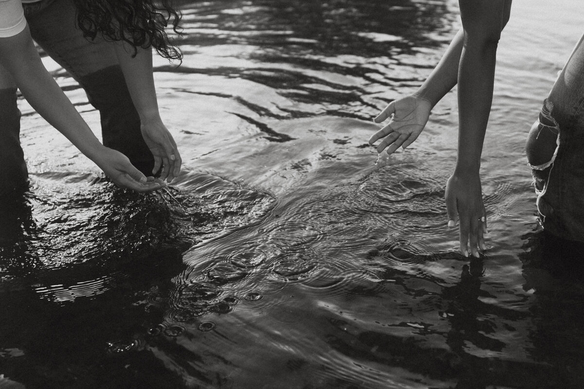 Two people leaning down and splashing water in a lake 