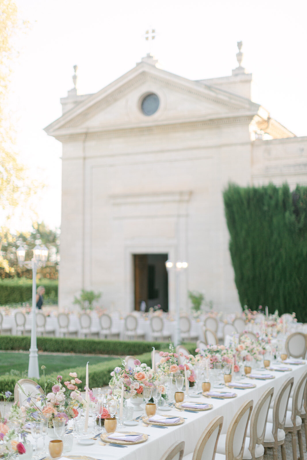 Luxury wedding dinner table in Provence courtyard decorated with pastel floral arrangements and candles.