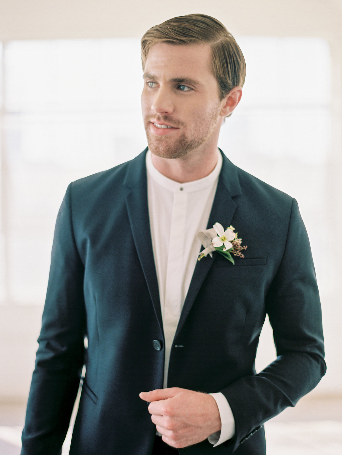 groom wearing a black modern slim fitting suit with shite collarless shirt