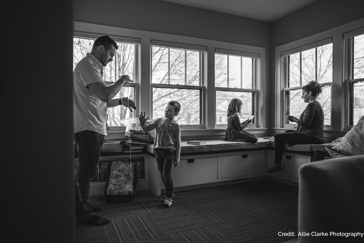 A black and white photo of a family sitting next to windows in their home
