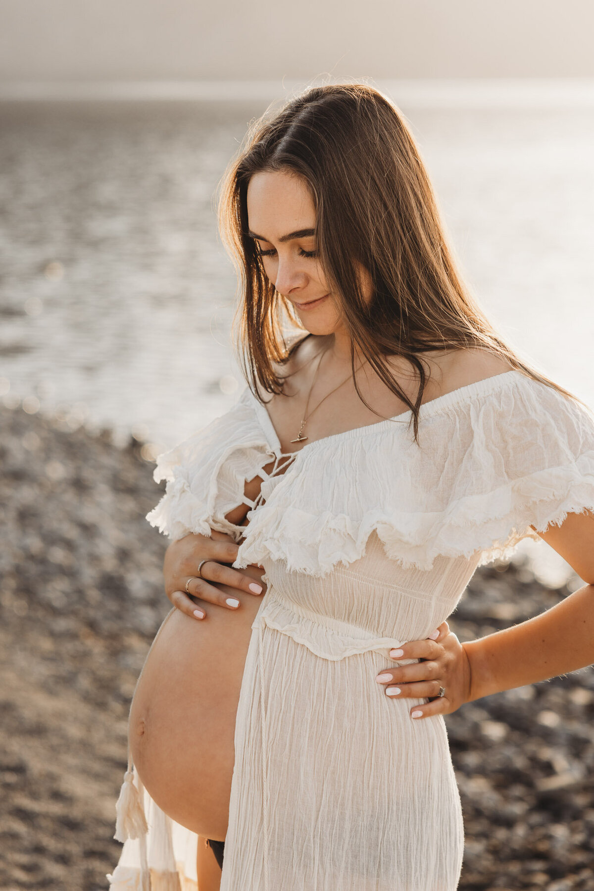 pregnant woman standing with hand on belly in wanaka during her maternity session