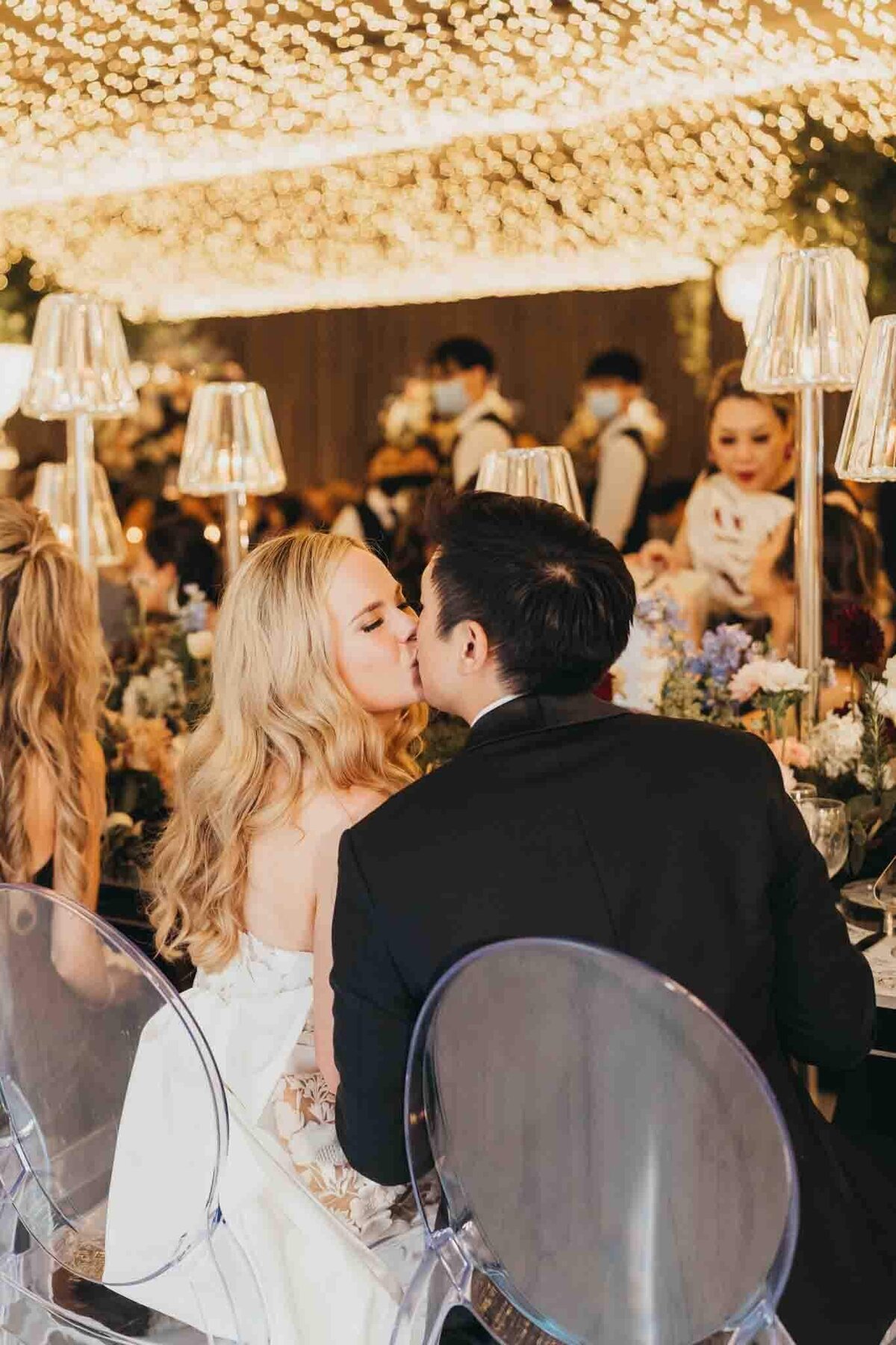 bride and groom kiss while seated at their dinner table
