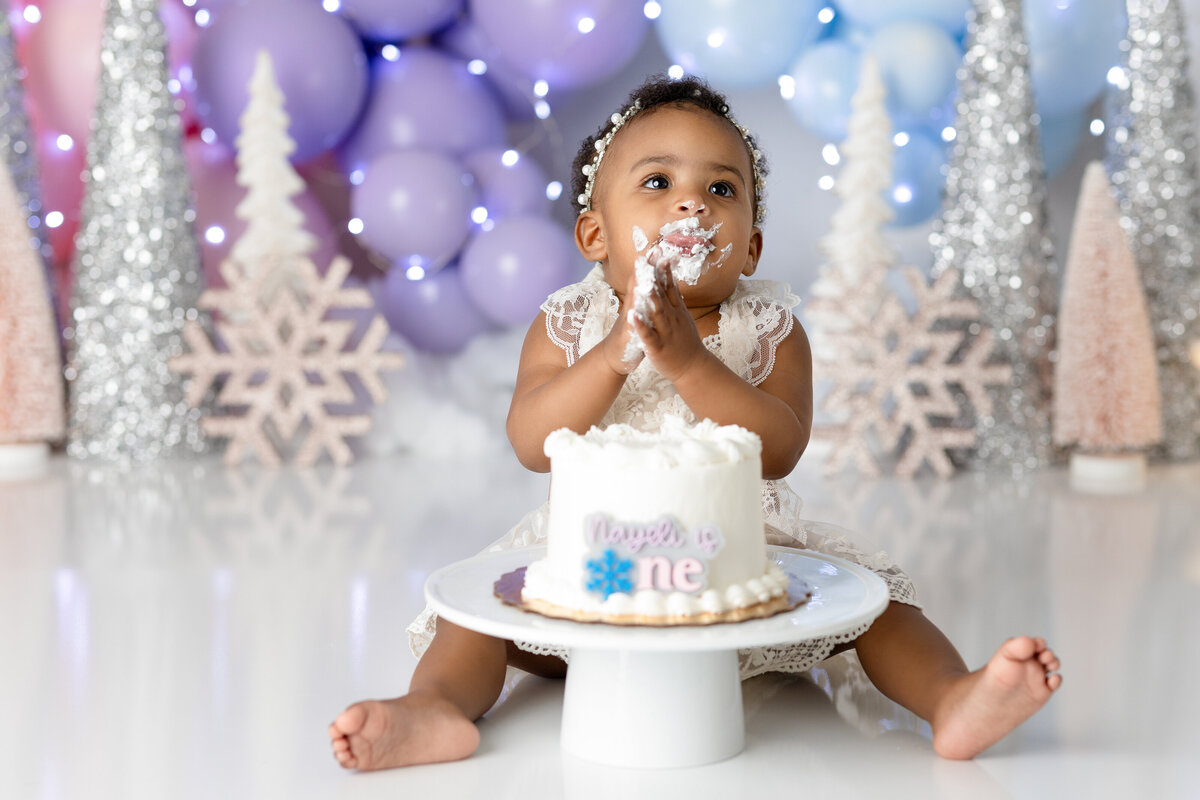 One year old Tampa baby enjoying a personalized luxury cake smash session with onederland decorations