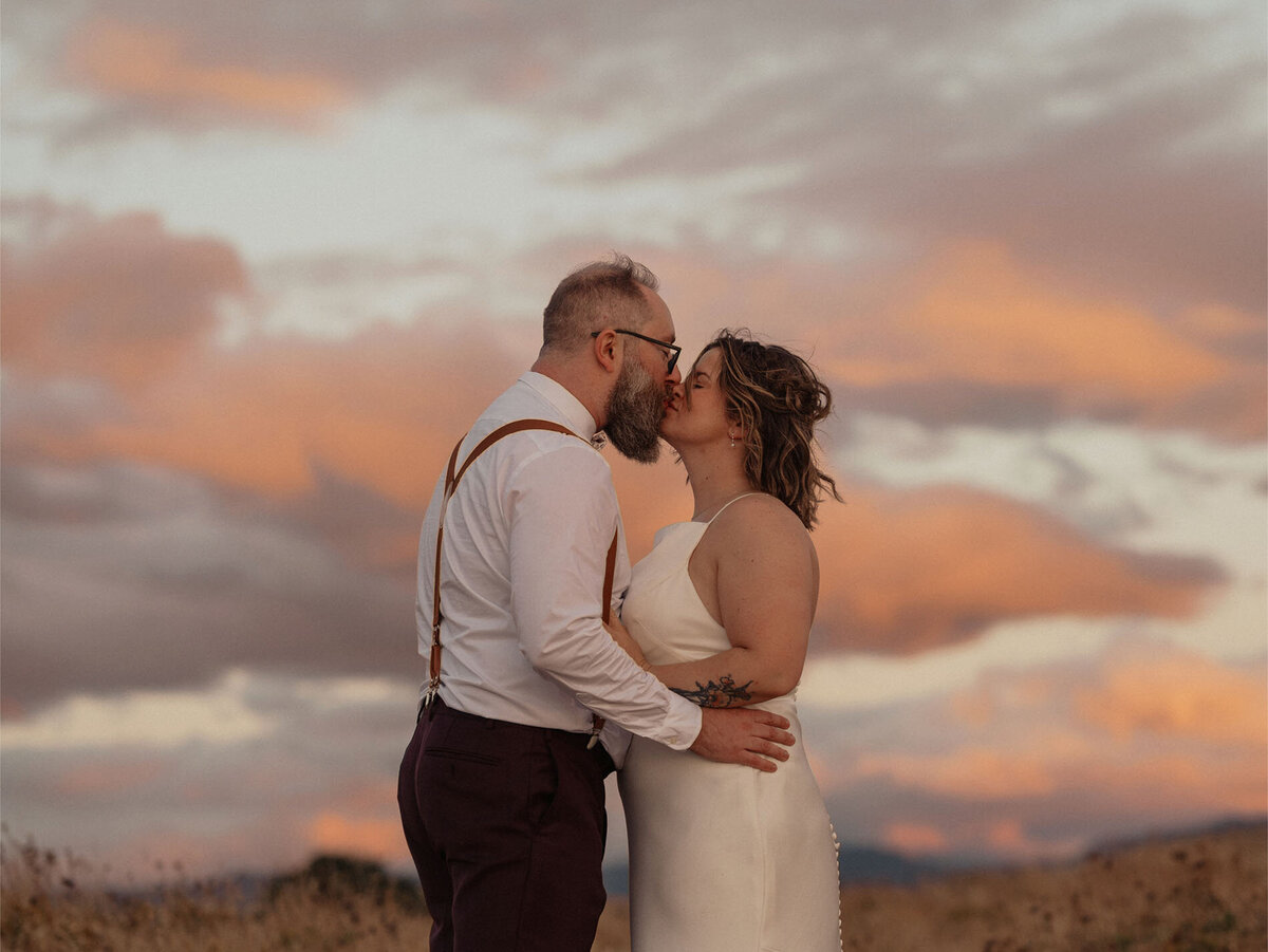elopement couple kissing and embracing under the cotton candy sky at Rowena Crest View Point in the Dalles, OR