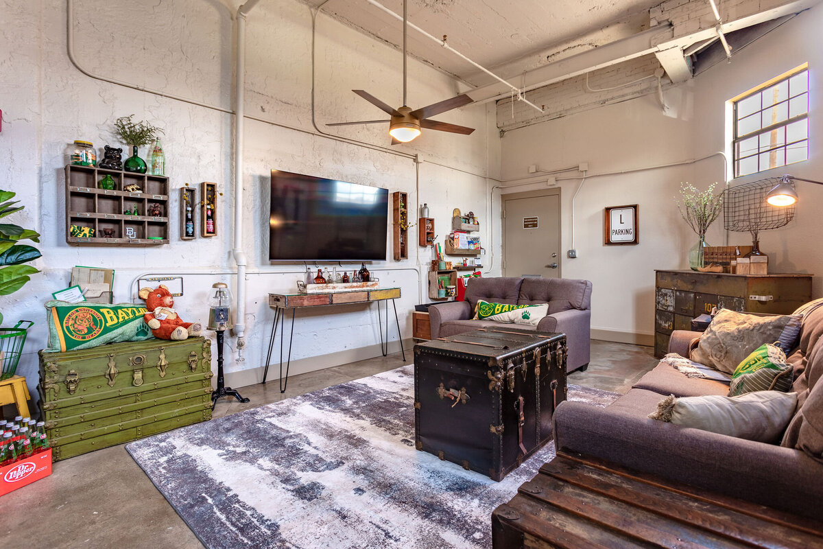 Living room with comfortable seating and smart TV in this 2-bedroom, 2-bathroom vacation rental condo for four guests in the historic Behrens building with free parking, free wifi, vintage decor, and easy access to Baylor University, Magnolia Silos, and Cameron Park Zoo in downtown Waco, TX.